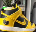 Yellow and black sneaker with Wu-Tang Clan logo next to a small statue of the Statue of Liberty.